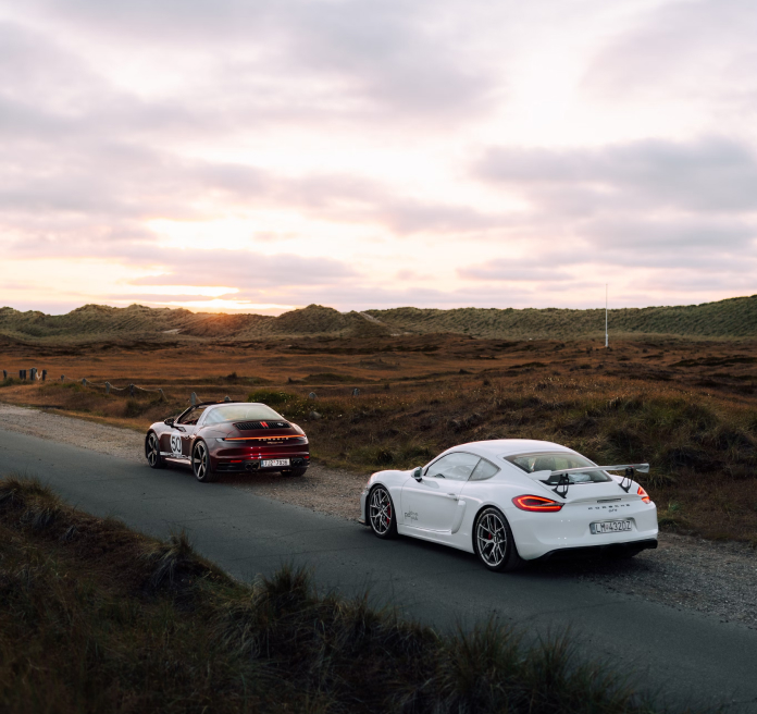 Image of two cars at sunset, one a Porsche Carrera and the other a Porsche, one behind the other.